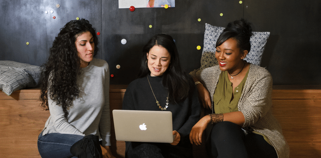 Photograph of 3 women sitting together looking at a computer 